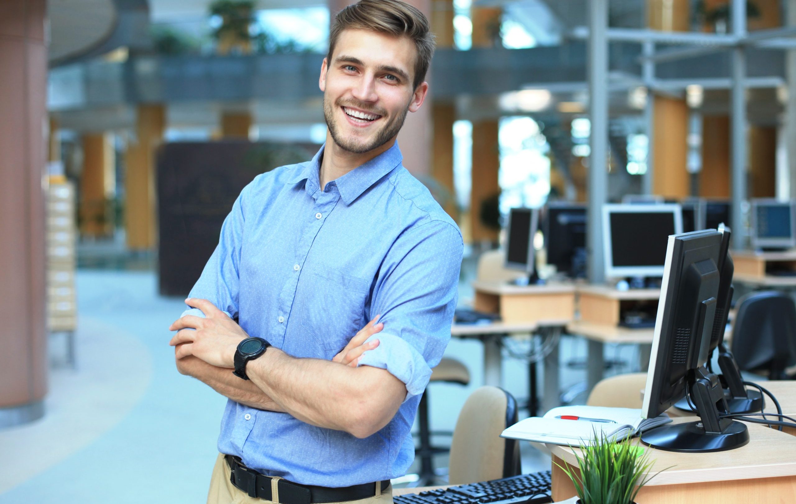 Young man posing confident and positive in professional workplace office with space.